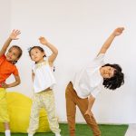 Joyful children stretching during indoor sport time in a classroom.