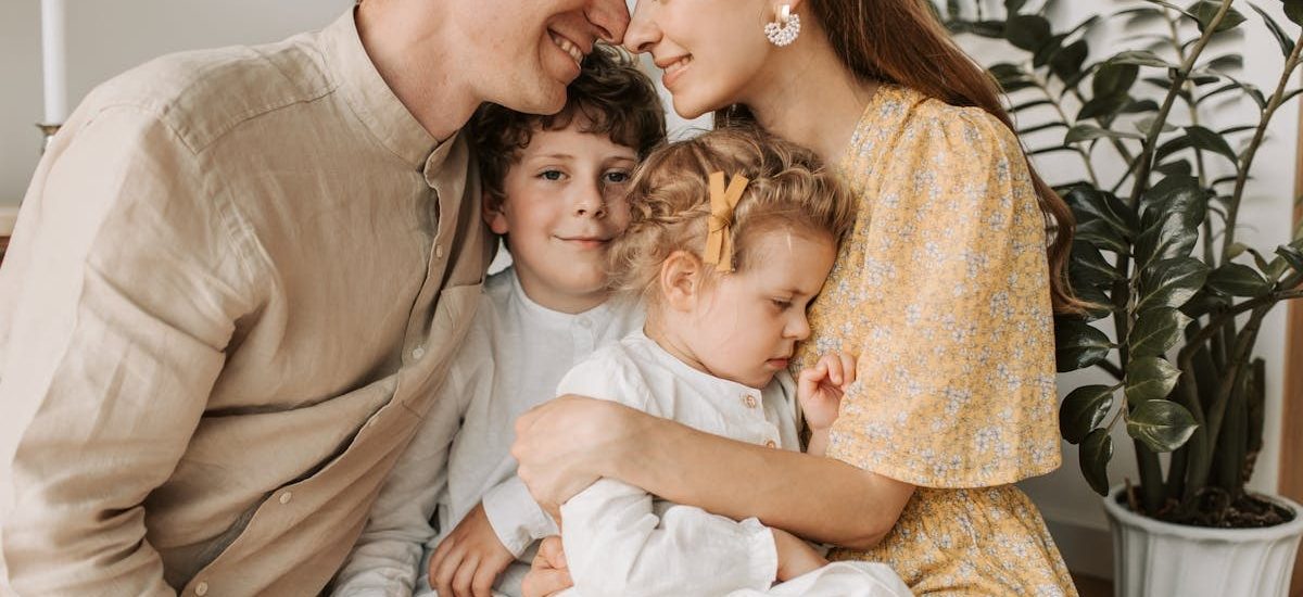 A loving family of four shares a tender moment in a cozy indoor setting, embracing and smiling.