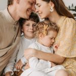 A loving family of four shares a tender moment in a cozy indoor setting, embracing and smiling.