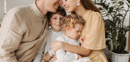 A loving family of four shares a tender moment in a cozy indoor setting, embracing and smiling.
