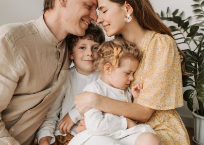 A loving family of four shares a tender moment in a cozy indoor setting, embracing and smiling.